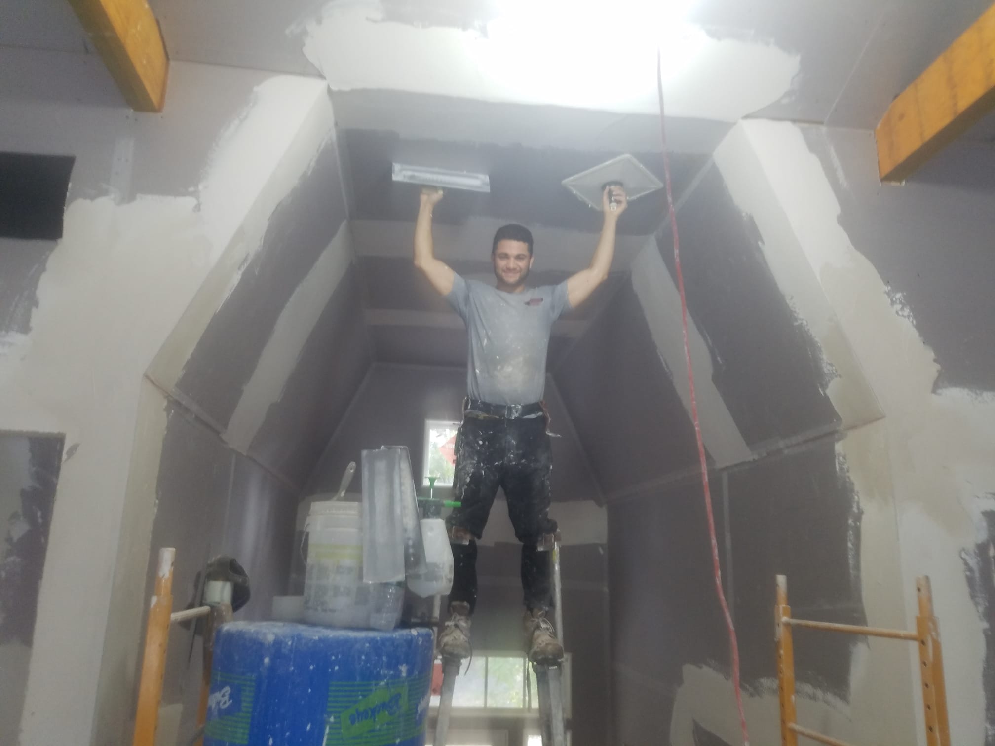 Bruno Silva, owner of Boston Strong Plastering, finishing a ceiling on stilts in Massachusetts