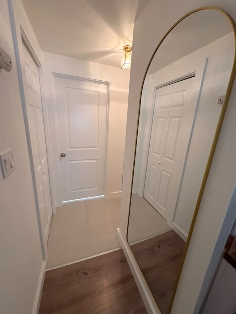Bright white painted walls and doors in a narrow hallway with wood flooring. by Boston Strong Plastering in Marblehead, MA